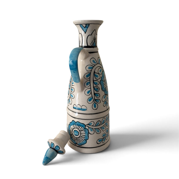 Blue and white ceramic decorative bottle with intricate floral patterns, a curved handle and matching stopper on a white background.