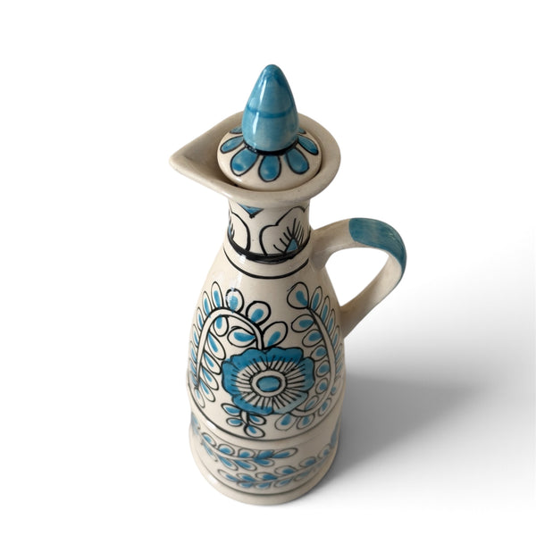 Blue and white ceramic decorative bottle with intricate floral patterns, a curved handle and matching stopper on a white background.